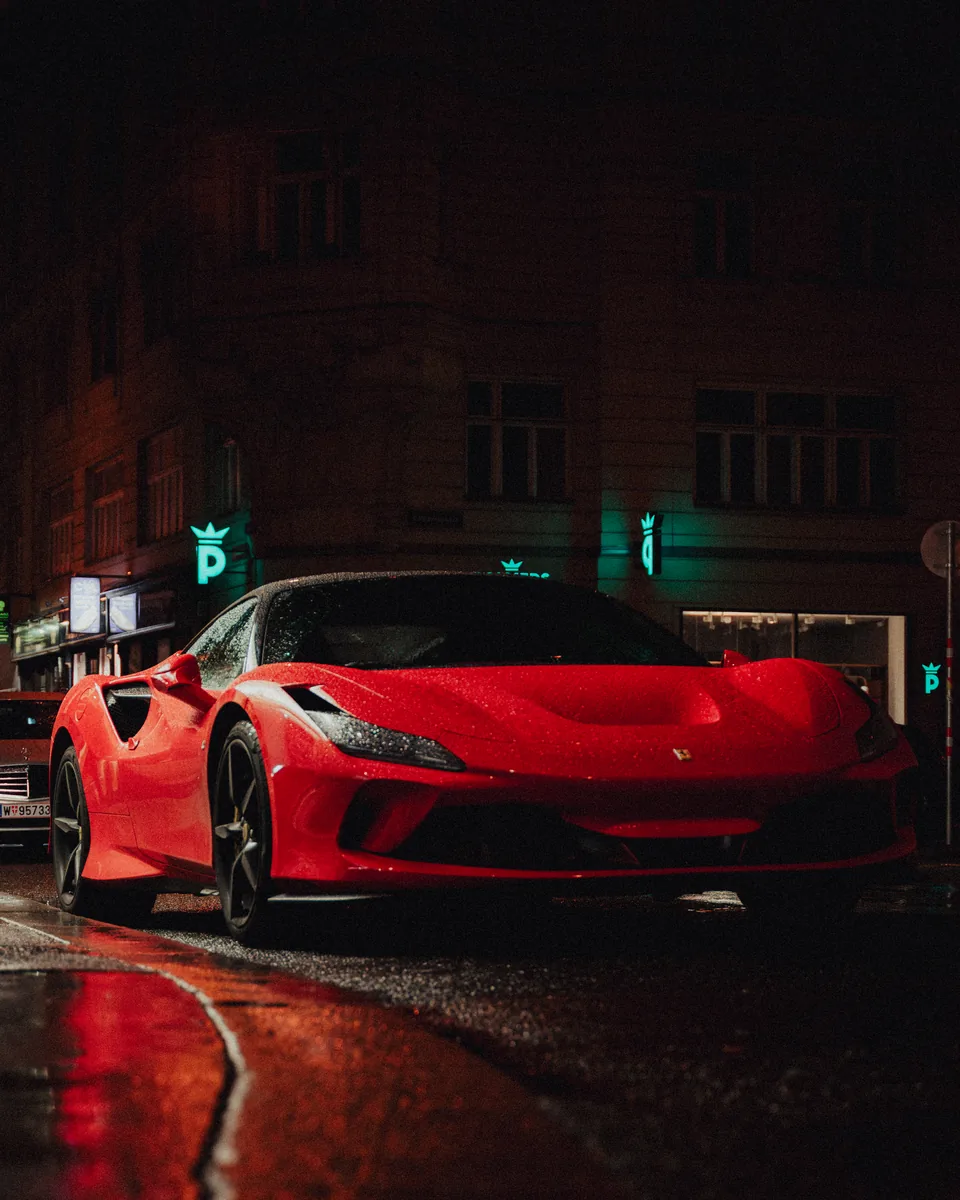 Roter Ferrari auf nasser Straße bei Nacht