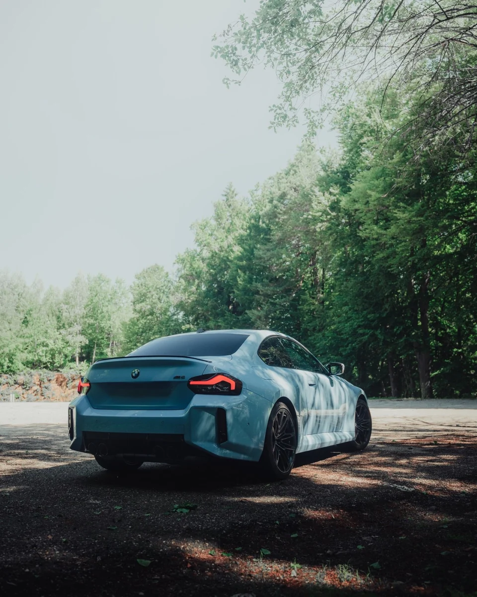BMW M2 Heckansicht im Waldlicht