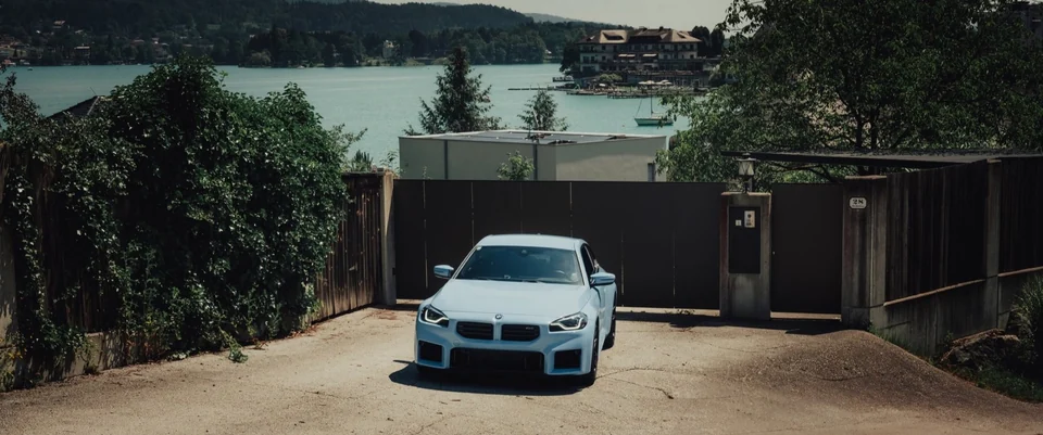 Weißer BMW M2 vor See und Villenlandschaft