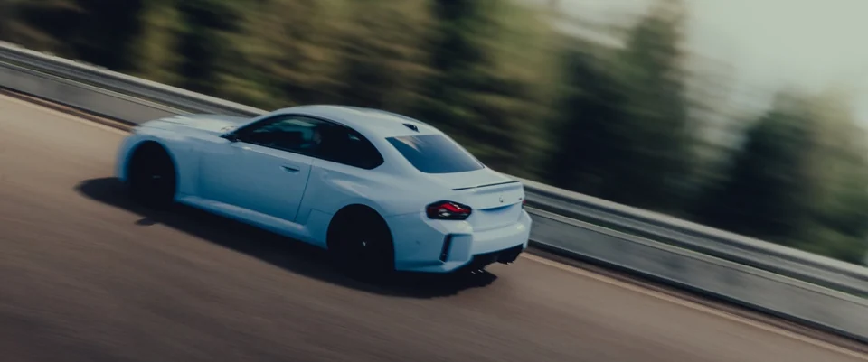 Weißer BMW M2 in Bewegung auf kurviger Straße